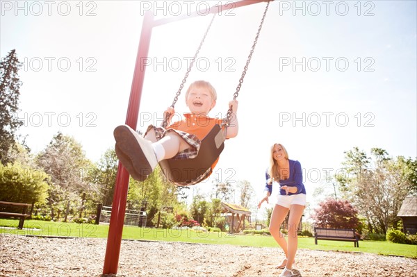 USA, Washington State, Seattle, Mother and son (2-3) swinging on swing in park. Photo: Take A Pix Media