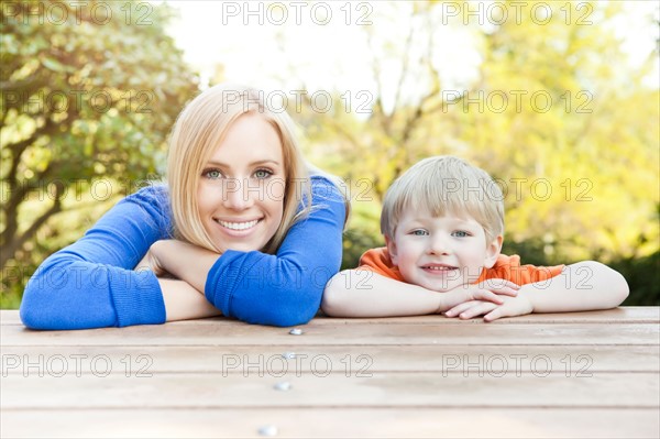Portrait of mother and son (2-3) leaning at picnic table. Photo : Take A Pix Media