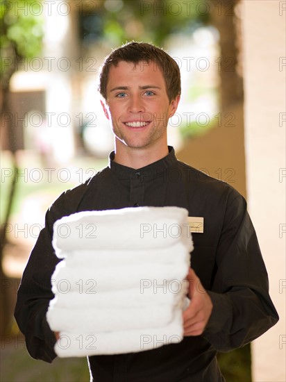 Man from room service delivering towels to hotel guest. Photo : db2stock