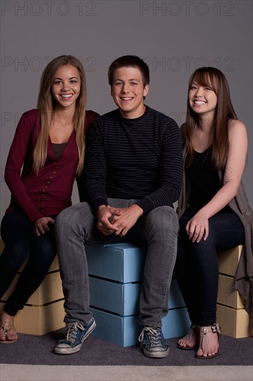 Portrait of teenage boy (16-17) and girl (16-17) with young friend, studio shot. Photo : Rob Lewine