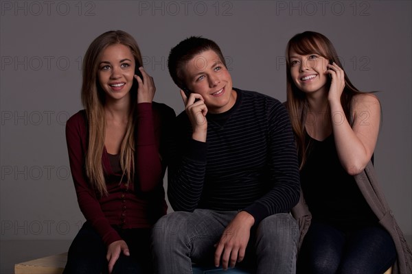 Portrait of teenage boy (16-17) and girl (16-17) with young friend, studio shot. Photo : Rob Lewine