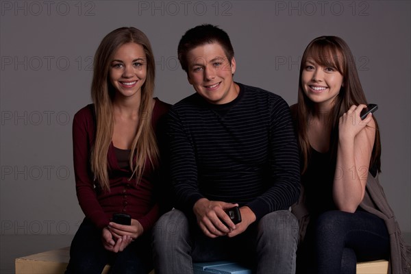 Portrait of teenage boy (16-17) and girl (16-17) with young friend, studio shot. Photo : Rob Lewine