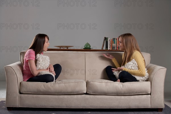 Portrait of teenage girl (16-17) and young woman sitting on sofa. Photo : Rob Lewine