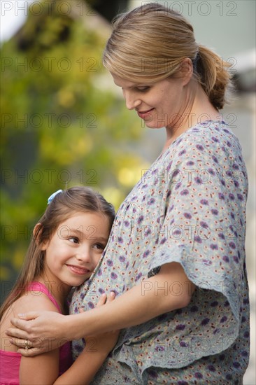 Pregnant mother and daughter (6-7) embracing . Photo : Rob Lewine