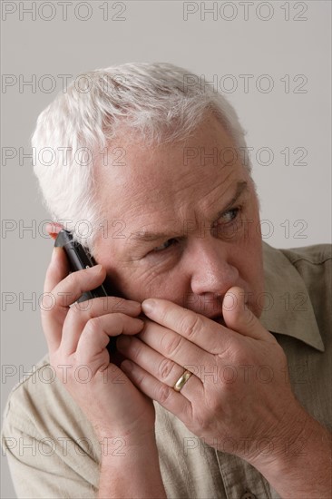 Portrait of senior man with mobile phone, studio shot. Photo : Rob Lewine