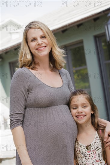 Portrait of pregnant mother and daughter (6-7)embracing. Photo : Rob Lewine