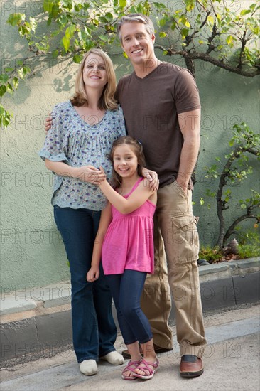 Pregnant mother, father and daughter (6-7) posing for portrait. Photo : Rob Lewine