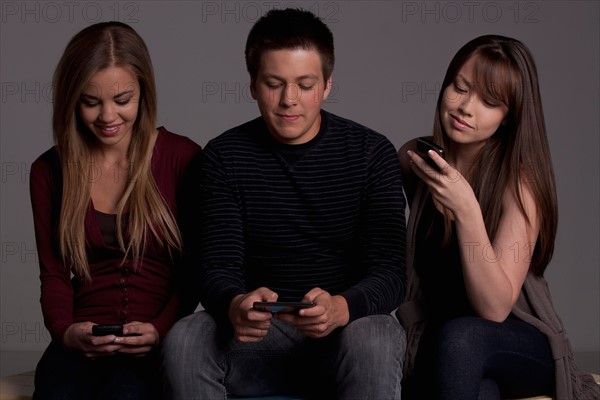 Portrait of teenage boy (16-17) and girl (16-17) with young friend, studio shot. Photo : Rob Lewine