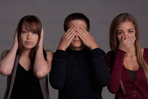 Portrait of teenage boy (16-17) and girl (16-17) with young friend, studio shot. Photo : Rob Lewine