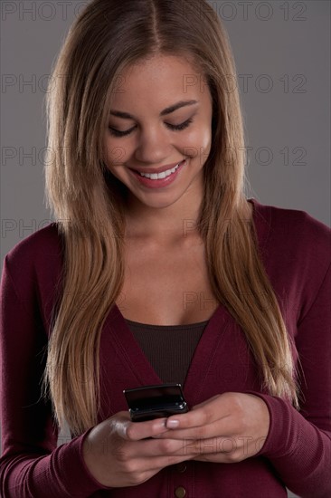 Portrait of teenage girl (16-17) with mobile phone, studio shot. Photo: Rob Lewine