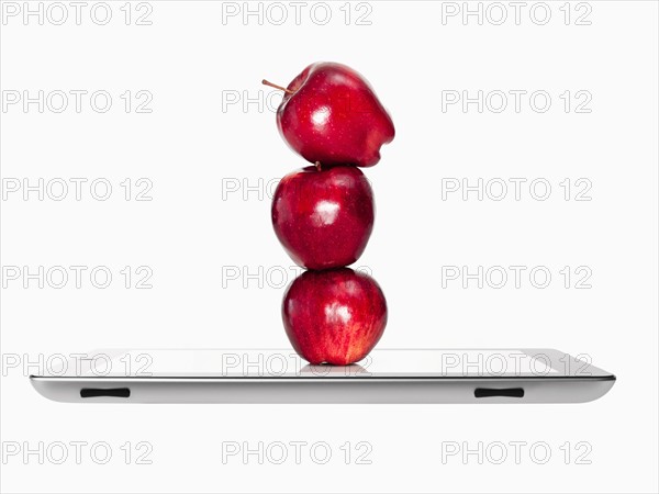 Apples on top of each other on digital tablet, studio shot. Photo : David Arky