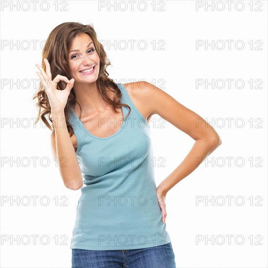 Studio portrait of attractive young woman showing ok sign. Photo : momentimages