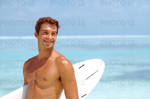 Shirtless young man holding surfboard. Photo : momentimages