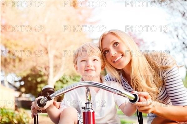 Mother and son (2-3) riding tricycle in park. Photo : Take A Pix Media