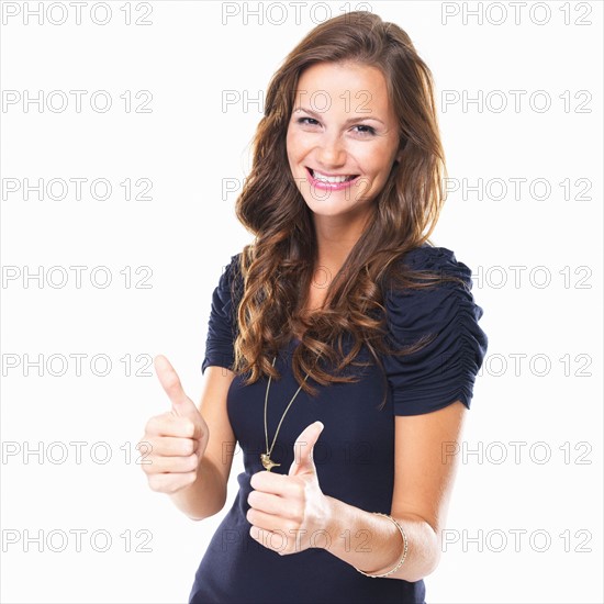 Studio shot of young woman with thumbs up. Photo : momentimages