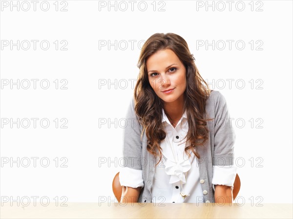 Portrait of attractive business woman sitting with hands under table. Photo: momentimages