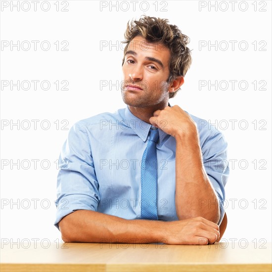 Business man sitting at table and touching collar. Photo : momentimages