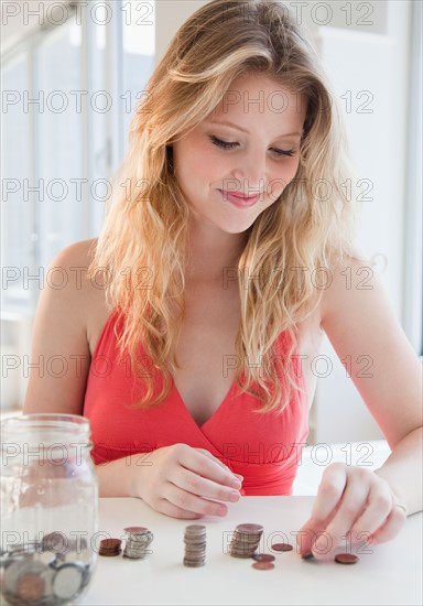 Young woman counting coins. Photo : Jamie Grill