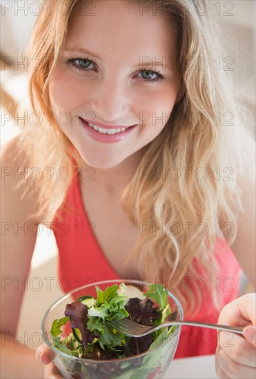 Young woman eating salad. Photo : Jamie Grill