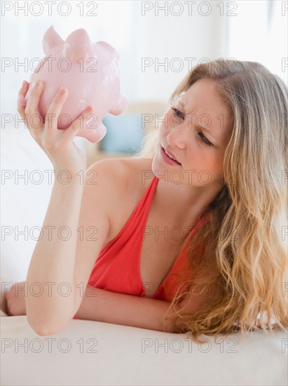 Young woman looking at piggybank. Photo: Jamie Grill