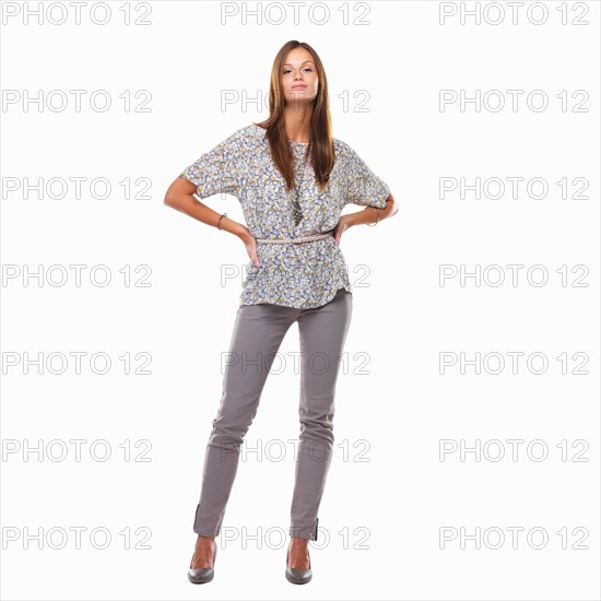 Studio shot of woman standing with hands on hips. Photo : momentimages