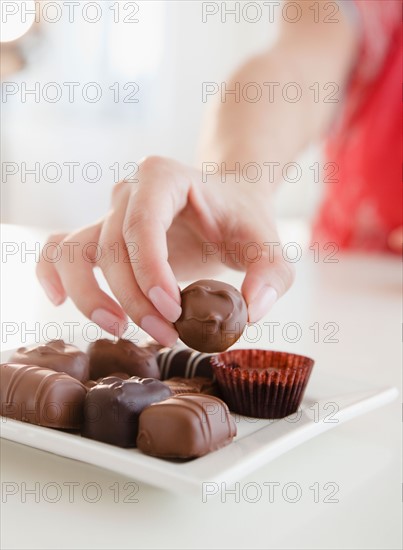 Woman taking praline. Photo : Jamie Grill