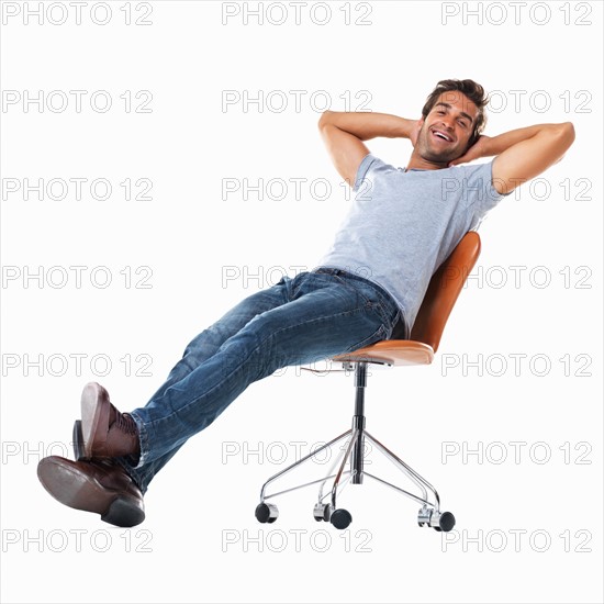 Studio shot of young man relaxing on chair. Photo: momentimages