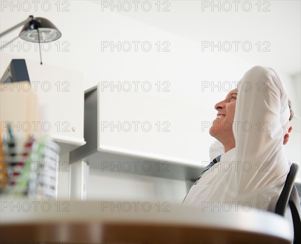 Businessman relaxing in office. Photo : Jamie Grill