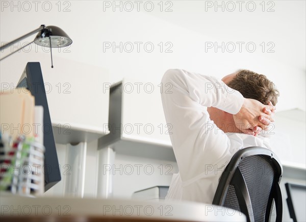 Businessman relaxing in office. Photo : Jamie Grill