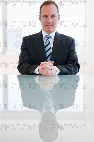 Businessman sitting at table. Photo : Jamie Grill