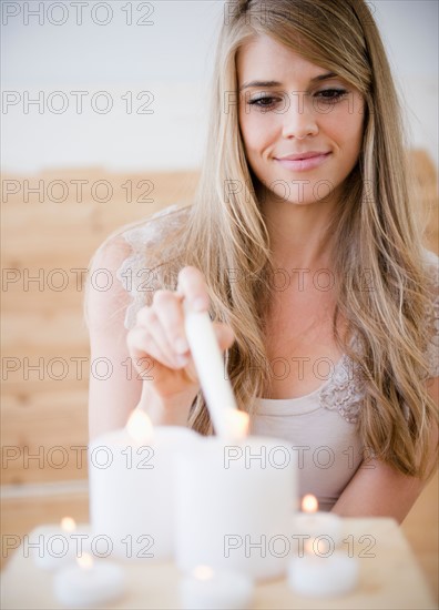 Woman igniting candles in spa. Photo : Jamie Grill