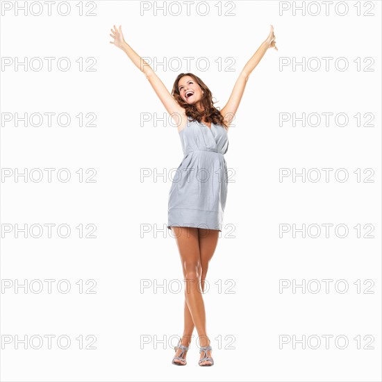 Studio shot of young excited woman celebrating success with hands raised. Photo: momentimages