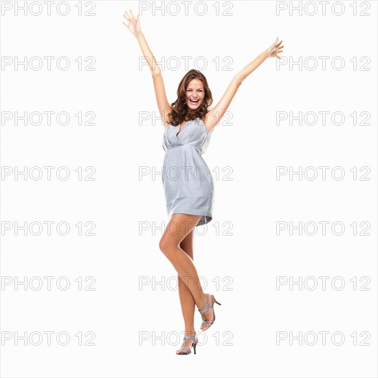 Studio shot of happy young woman celebrating with hands raised. Photo : momentimages