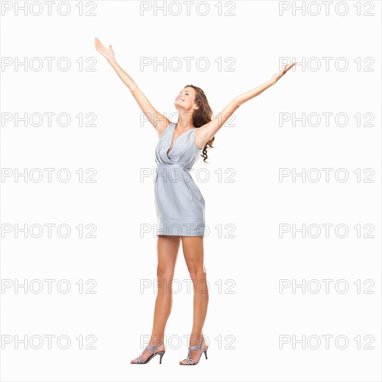 Studio shot of young woman standing with arms outstretched and enjoying the moment. Photo: momentimages