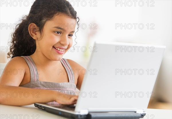 Girl (8-9) using laptop.