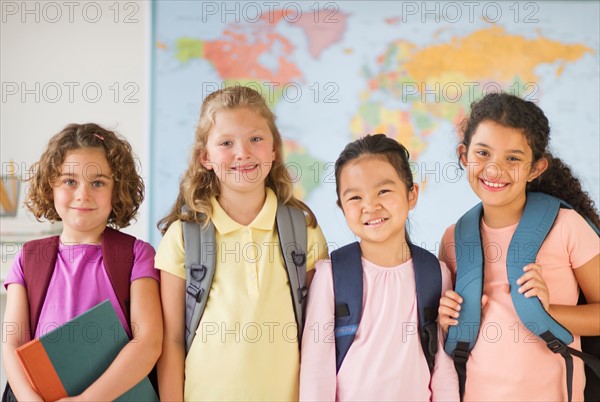 Portrait of four girls (6-9) carrying backpacks.