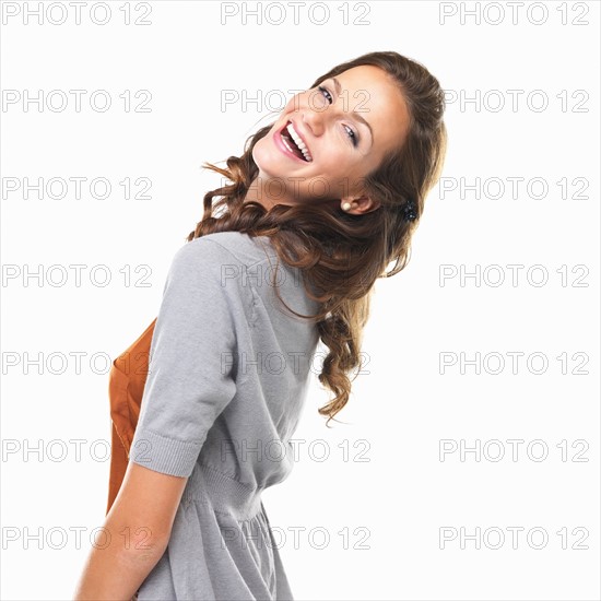 Studio portrait of happy young woman looking over shoulder and smiling. Photo : momentimages