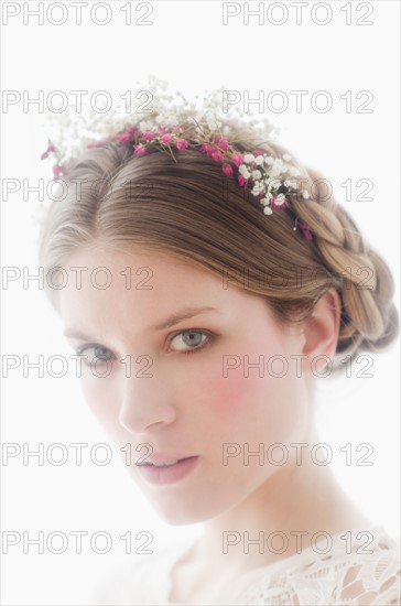 Studio portrait of young woman with flowers in hair.