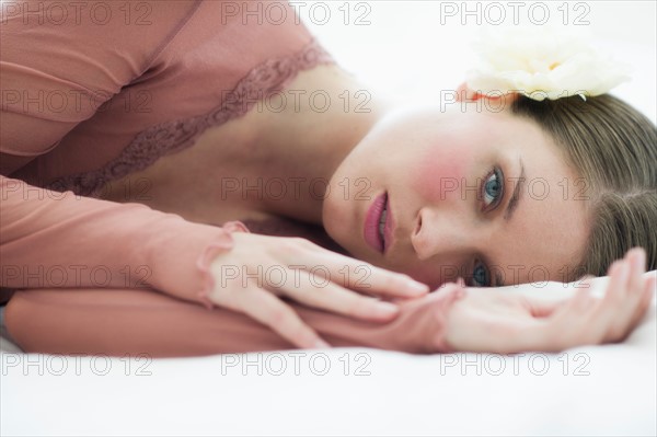 Studio portrait of young woman lying on bed.