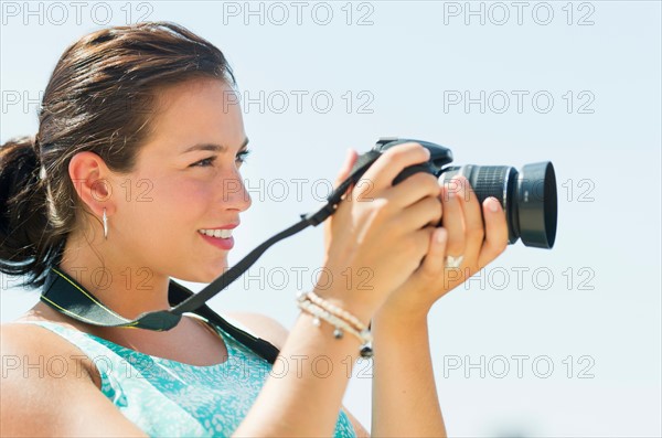 Portrait of young woman taking pictures with camera.