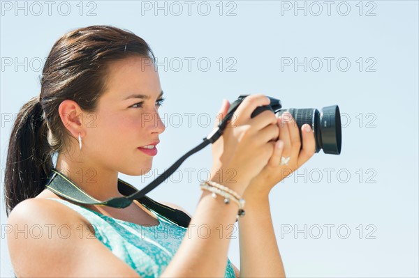 Portrait of young woman taking pictures with camera.