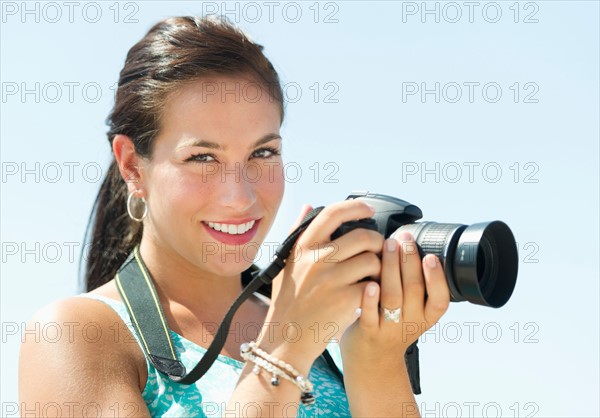 Portrait of young woman taking pictures with camera.