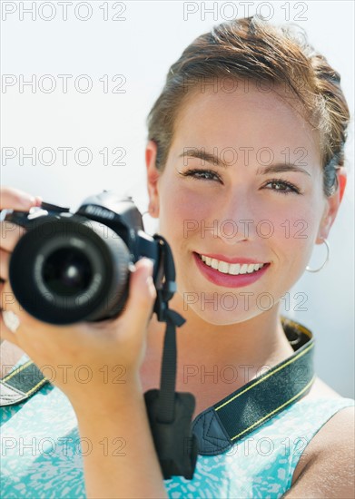 Portrait of young woman taking pictures with camera.