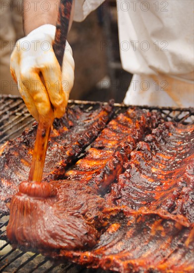 Chef cooking spareribs on barbeque.