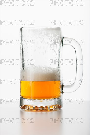 Studio shot of half-full beer glass.