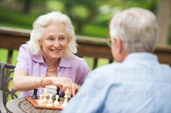 Seniors playing chess on porch.