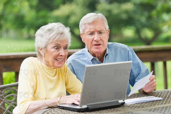 Senior couple using laptop on porch.