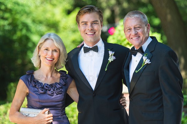 Portrait bridegroom with parents at wedding.