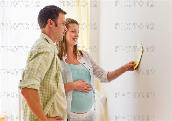 Young couple choosing wall color for nursery.