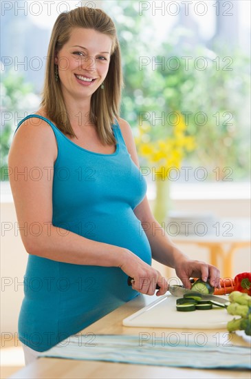 Young pregnant woman preparing food.